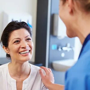 Smiling patient interacting with a healthcare professional in a clinical setting, representing the supportive environment of Emerald Coast Foot and Ankle Center's podiatric care services.